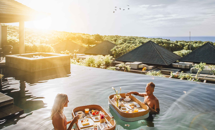 Wanita dan pria menikmati sarapan apung di kolam renang luar ruangan vila